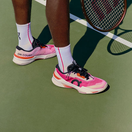 Person wearing pink and black On The Roger Pro Fire tennis shoes on a tennis court