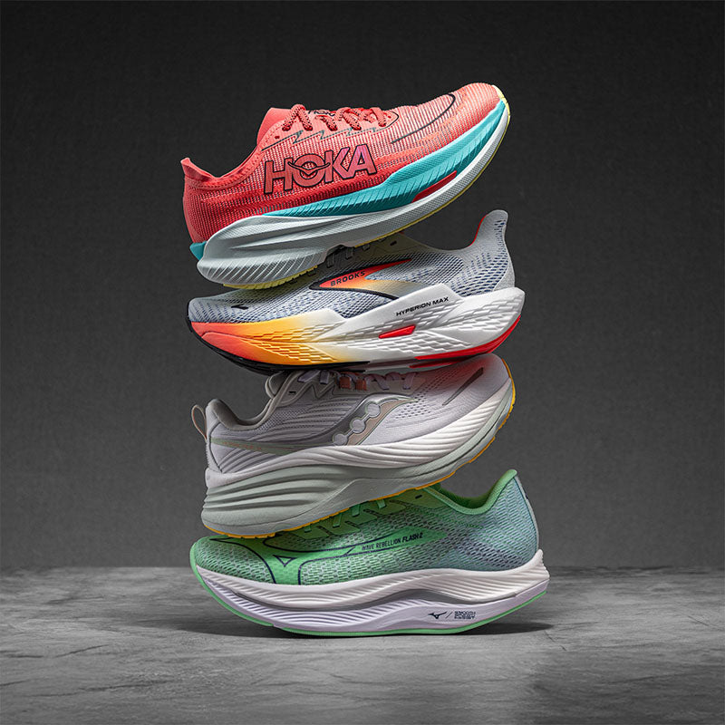 Stack of colorful HOKA, Brooks, Saucony and Mizuno running shoes