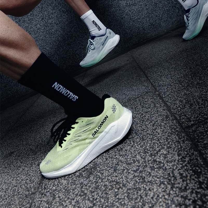 People running on a tiled surface wearing Salomon Aero Blaze 4 running shoes