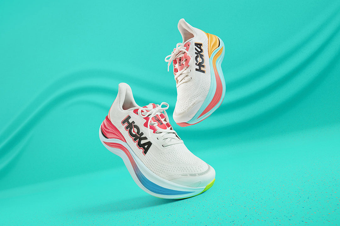 An image showcasing the Hoka Skyward X shoe, featuring both men's and women's styles floating in front of a vibrant and colorful background, highlighting the shoe's design
