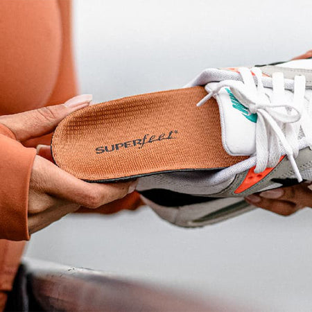 Person holding a shoe with 'Superfeet' insole label