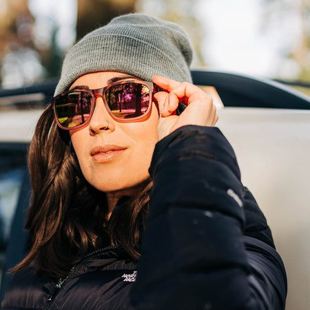 Person wearing a beanie, jacket and Tifosi Swank XL Pink Tortoise sunglasses with a blurred background