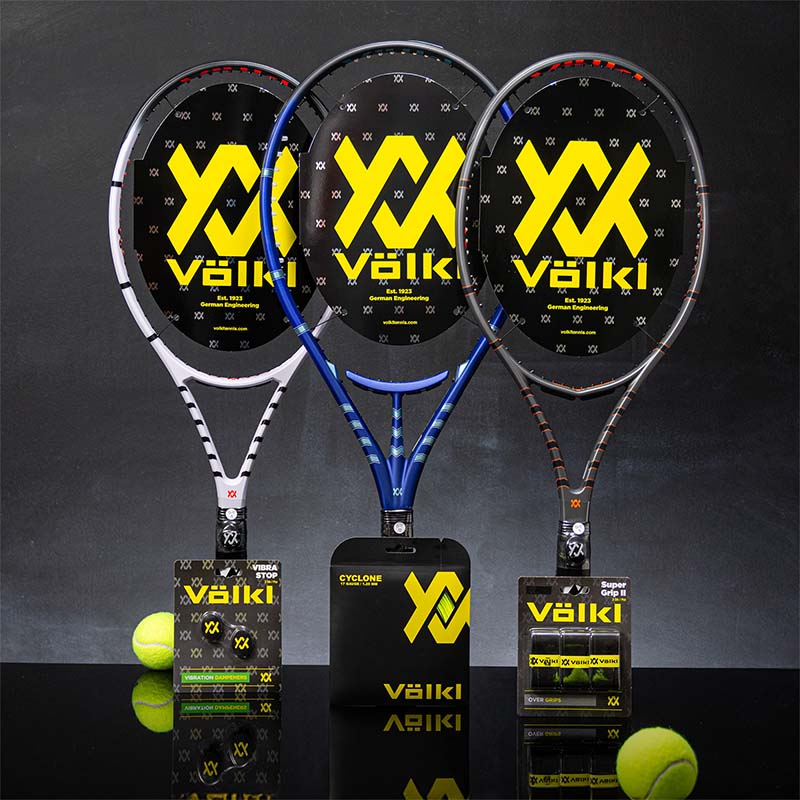 Three Volkl Vostra tennis racquets with string and grip packages and balls on a dark background