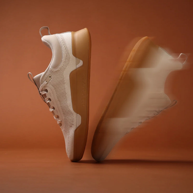 Pair of beige while on earth move trainer sneakers on an orange background
