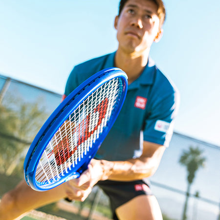 Person holding a Wilson Ultra v5 tennis racquet with a blurred background
